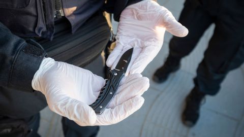 A member of the dog squad holds a confiscated knife in his gloved hands.